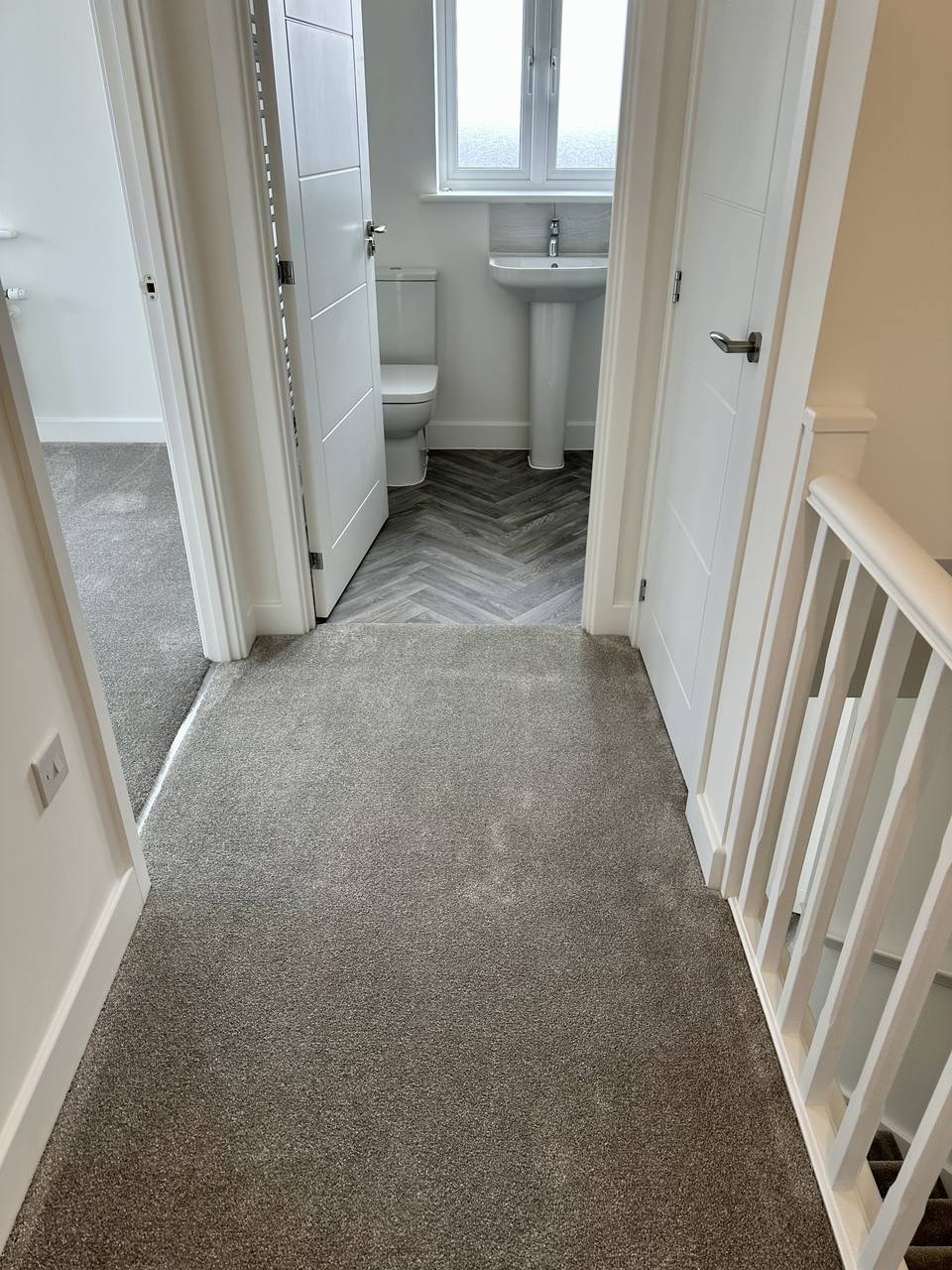 Carpeted landing with a herringbone bathroom floor beyond